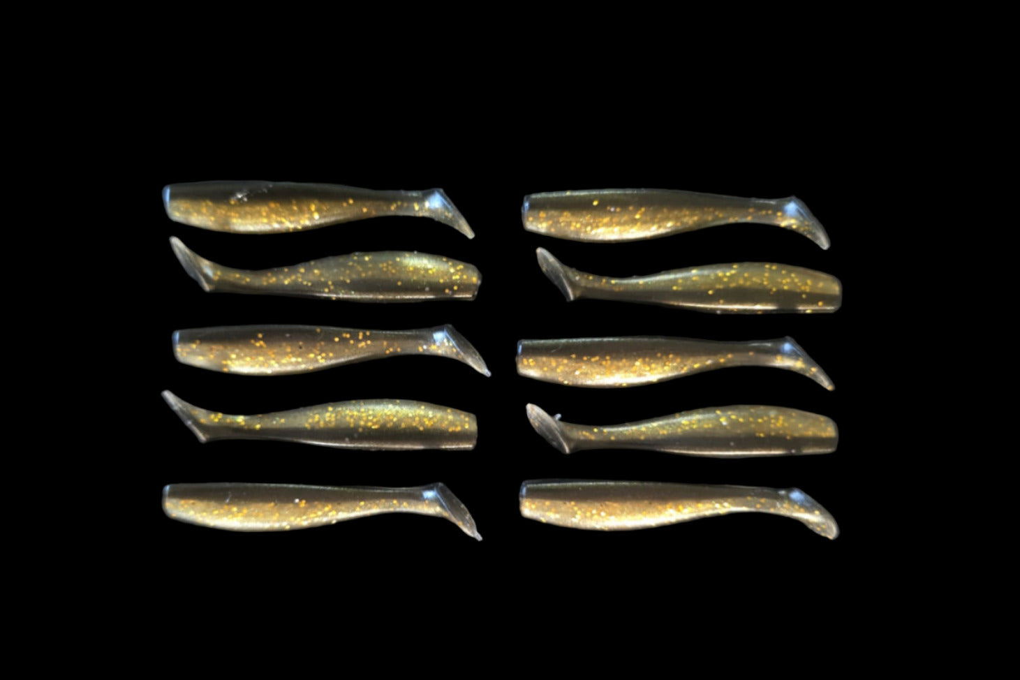 Row of metallic gold and silver fishing lures on a black background